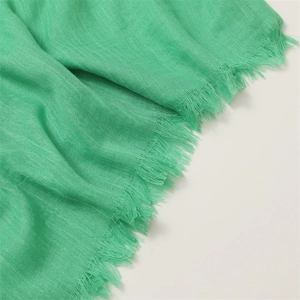 Detailed close-up of the green cotton linen scarf showing delicate fringe edges and texture