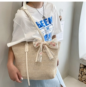 Lace bow detail and embroidery on beige straw tote bag with white leather strap