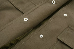 Close-up of military green bomber jacket with silver metal snap button and stitching
