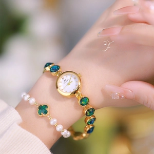 Detail of luxury gold lady watch with malachite stones and a pearl clover bracelet