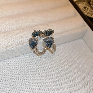 Close-up of blue heart-shaped glass beads arranged in a flower pattern on silver earrings