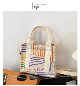Detail of corduroy crossbody bag with colorful stripes resting on a wooden ukulele