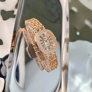 Detailed view of luxury rose gold oval watch with crystal embellishments on a metallic tray