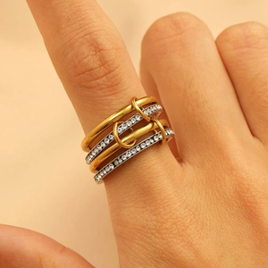 Close-up of interlocking gold and silver rings with pave set zircon stones on finger