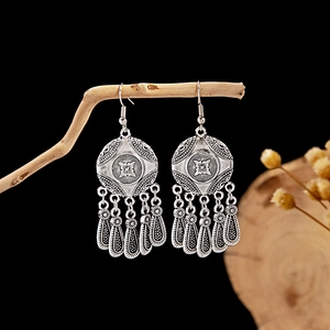 Detailed view of silver bohemian tassel earrings hanging on a rustic branch decoration