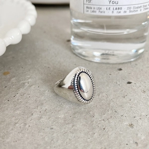 Vintage oval signet ring in 925 sterling silver with radial texture on a grey surface