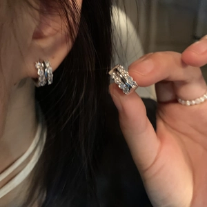 Detailed view of silver hoop earrings featuring multiple rows of cubic zirconia stones