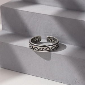 Detailed view of wave-patterned vintage 925 silver ring on a minimalist grey background