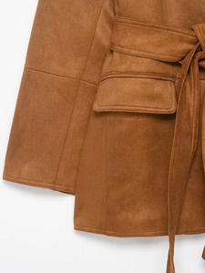Detailed close-up of brown suede blazer featuring waist belt, flap pockets and sleeve cuffs