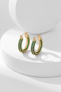 Macro shot of gold-plated hoop earrings with three rows of pavé-set green cubic zirconia