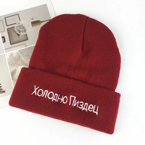 Detail of red knit beanie with white Russian embroidery and soft ribbed texture