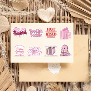 Flat lay of pink bookish stickers with heart and dinosaur motifs on a textured mat