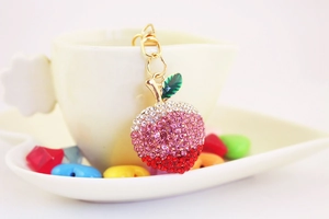 Sparkling rhinestone apple keychain hanging on a ceramic cup for elegant gift presentation
