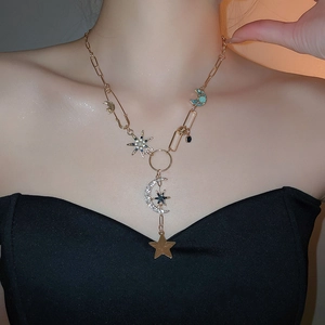 Gros plan des pendentifs étoile et lune scintillants sur un collier en or porté