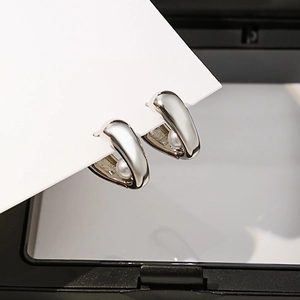 Détail d'une boucle d'oreille cœur géométrique en argent avec perle sur coffret noir
