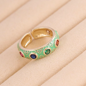 Golden ring with colorful zircons and green enamel coating in retro luxury style