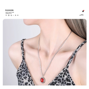 Detail of a red round stone pendant on a silver twisted rope chain necklace worn by a model