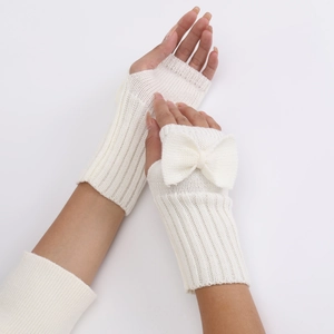 Detailed view of cream-white knitted fingerless gloves with a decorative bow detail