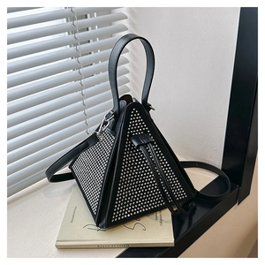 Macro view of triangular black handbag with silver studs resting on a French book