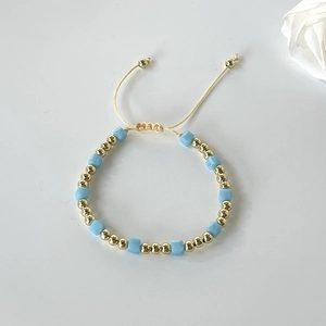 Detail of adjustable light blue frosted cube beads and polished gold beads on string