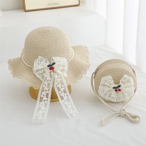 Detail of straw hat and round bag set with white lace bows and cherry embroidery
