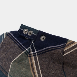 Macro shot of multi-color plaid fabric texture with silver metal snap buttons and navy trim