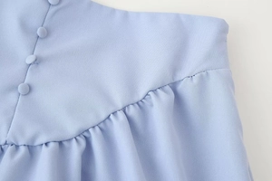 Detail of light blue woven fabric with fabric-covered buttons and ruffled pleated seams