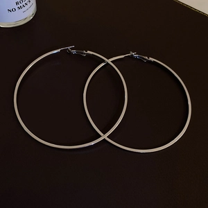 Macro shot of silver large hoop earrings featuring high polished metallic finish