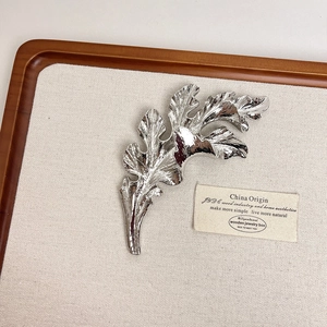 Close-up of a glossy silver leaf brooch with realistic texture and metallic shine
