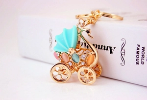 Detail of a golden metal stroller keychain with rhinestones and colorful gemstones
