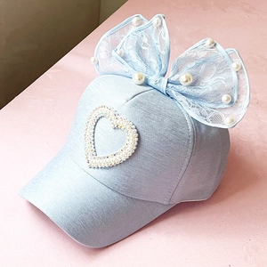 Detailed view of light blue girls baseball cap with lace bow and pearl heart patch