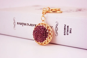 Detail of round keychain with purple rhinestones and gold-tone hollow engraving