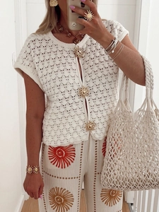 Detail of white hollow knit short-sleeve cardigan with golden sun-shaped decorative buttons