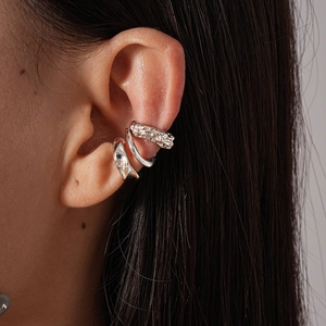 Close-up of silver irregular geometric ear cuff with spiral texture worn by a model