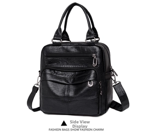 Detail view of the black soft leather bag showing double handles and front zipper pockets