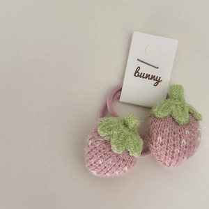 Detailed macro view of two handmade knitted pink strawberry hair ties with green leaves