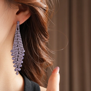 Gros plan d'un mannequin portant des boucles d'oreilles pendantes en cristal violet luxe
