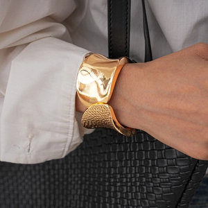 Detail of gold irregular textured bangle with polished finish and hammered metal surface