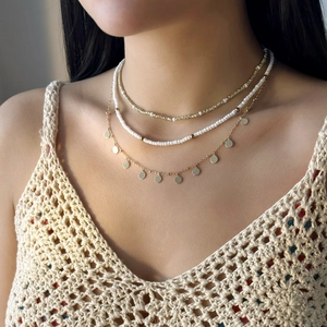 Détail de colliers superposés avec perles et étoile de mer portés par un mannequin au soleil