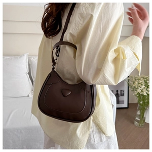 Detail of dark brown crescent bag with 3D heart decor and fine stitching on PU leather