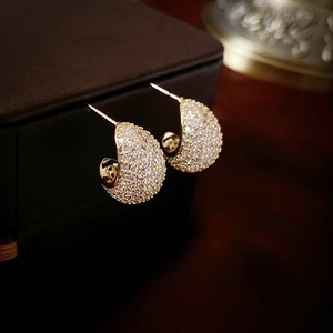 Macro shot of gold plated C-shaped earrings with micro-pave crystal inlay details