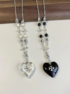 Detail of gothic heart pendants with cross motifs on wood and beige background