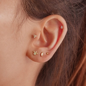 Detail of 925 sterling silver opal stud earrings in gold finish on ear cartilage