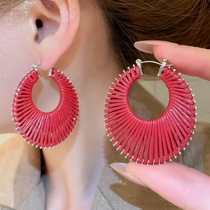 Détail de boucles d'oreilles géométriques tissées rouges avec fermoir métal