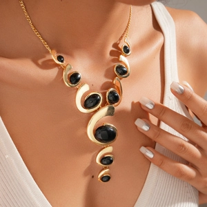 Close-up of a model wearing a gold chunky necklace with black oval resin stones