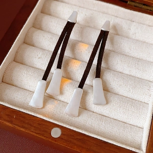 Close-up of vintage leather cord tassel earrings with silver trapezoid metal pendants