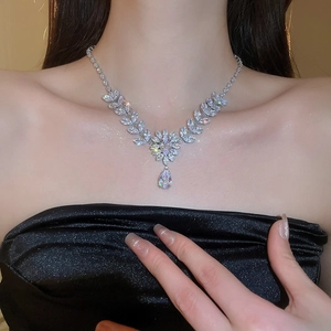 Close-up of elegant leaf and flower zircon necklace with teardrop pendant on model