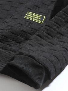 Detail of black textured fabric with yellow graphic patch and geometric knit pattern
