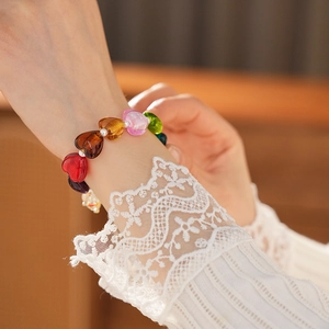 Detail of colorful glass heart beads bracelet worn by model with lace cuff