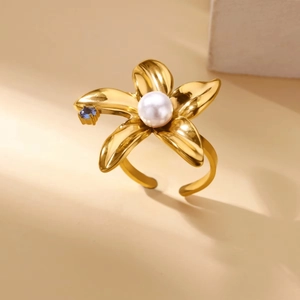 Detail of gold floral ring with white pearl center and blue gemstone on open band
